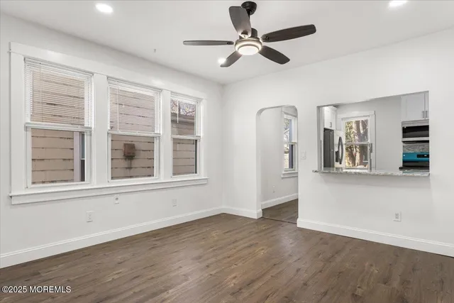 a view of an empty room with a window and wooden floor