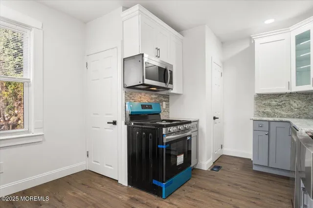a kitchen with stainless steel appliances granite countertop a stove and a wooden floor