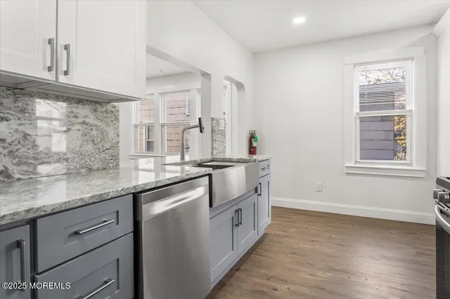 a kitchen with granite countertop cabinets stainless steel appliances a sink and a window