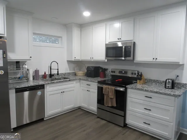 a kitchen with granite countertop white cabinets and stainless steel appliances