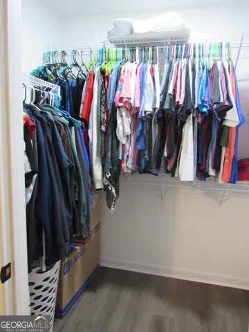 a view of walk in closet with clothes and shoes