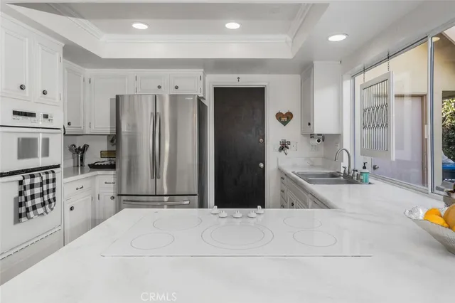 a large white kitchen with stainless steel appliances kitchen island granite countertop a refrigerator and a sink