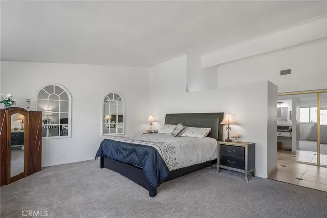 a bedroom with a bed and large windows