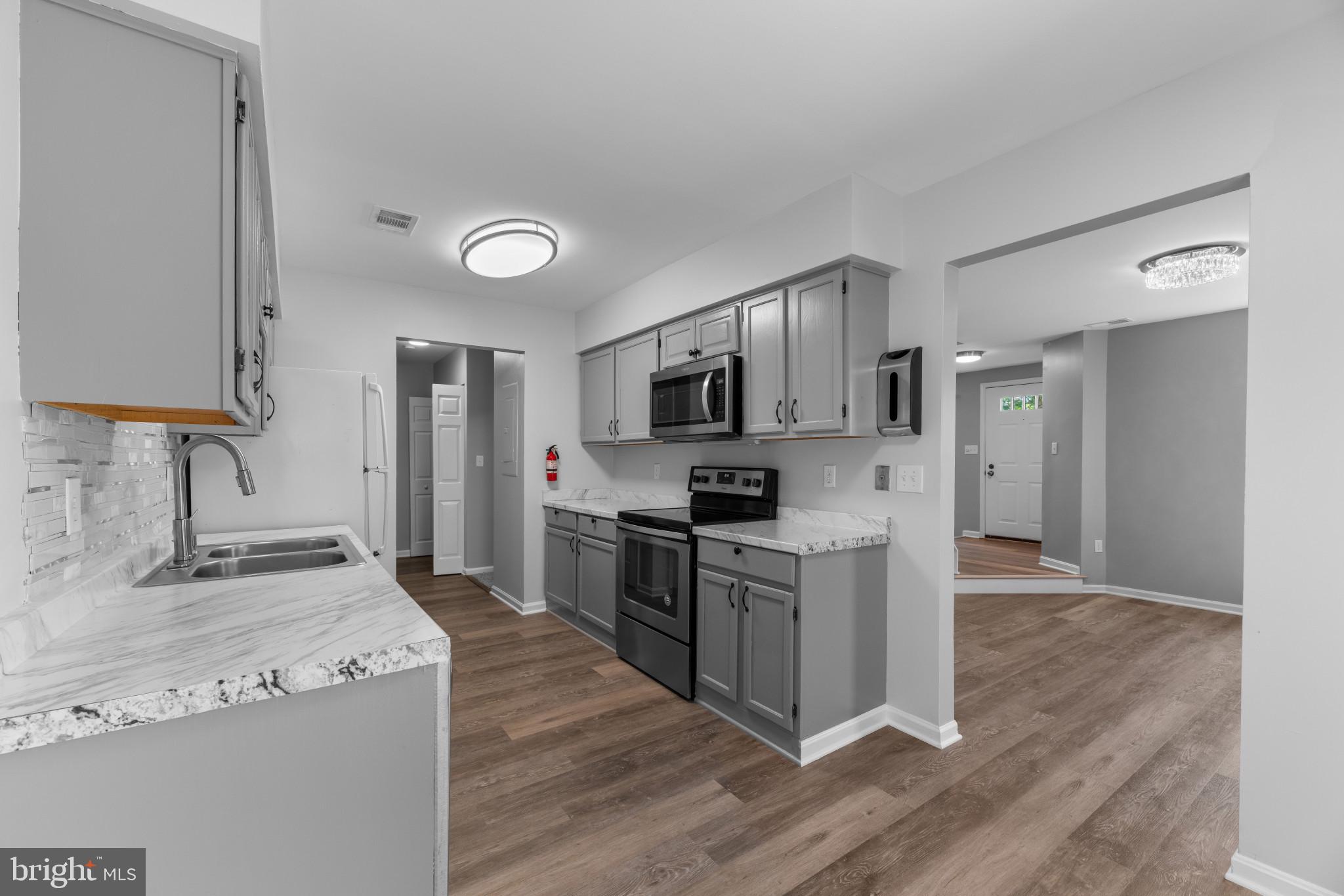 9302 Player Drive, Unit 155 Laurel, MD 20708 - Photo 12 of 43 a kitchen with stainless steel appliances granite countertop a stove top oven a refrigerator a sink and dishwasher