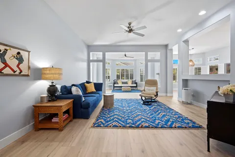 a living room with furniture and a lamp on table with wooden floor