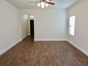 an empty room with wooden floor chandelier and windows