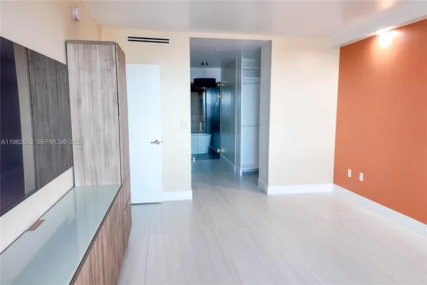 a view of a hallway with wooden floor and a bathroom