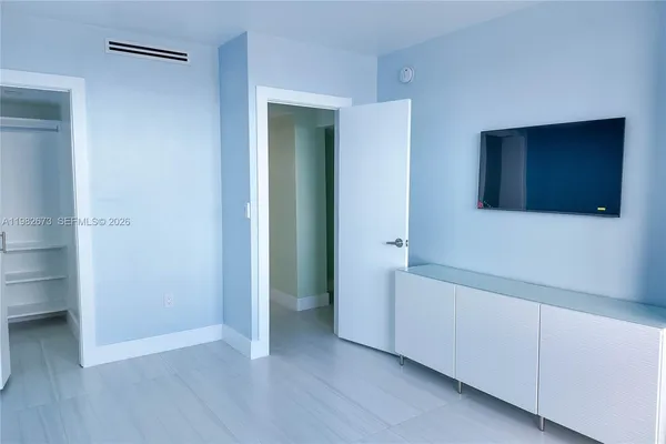 a view of an empty room with closet and wooden floor
