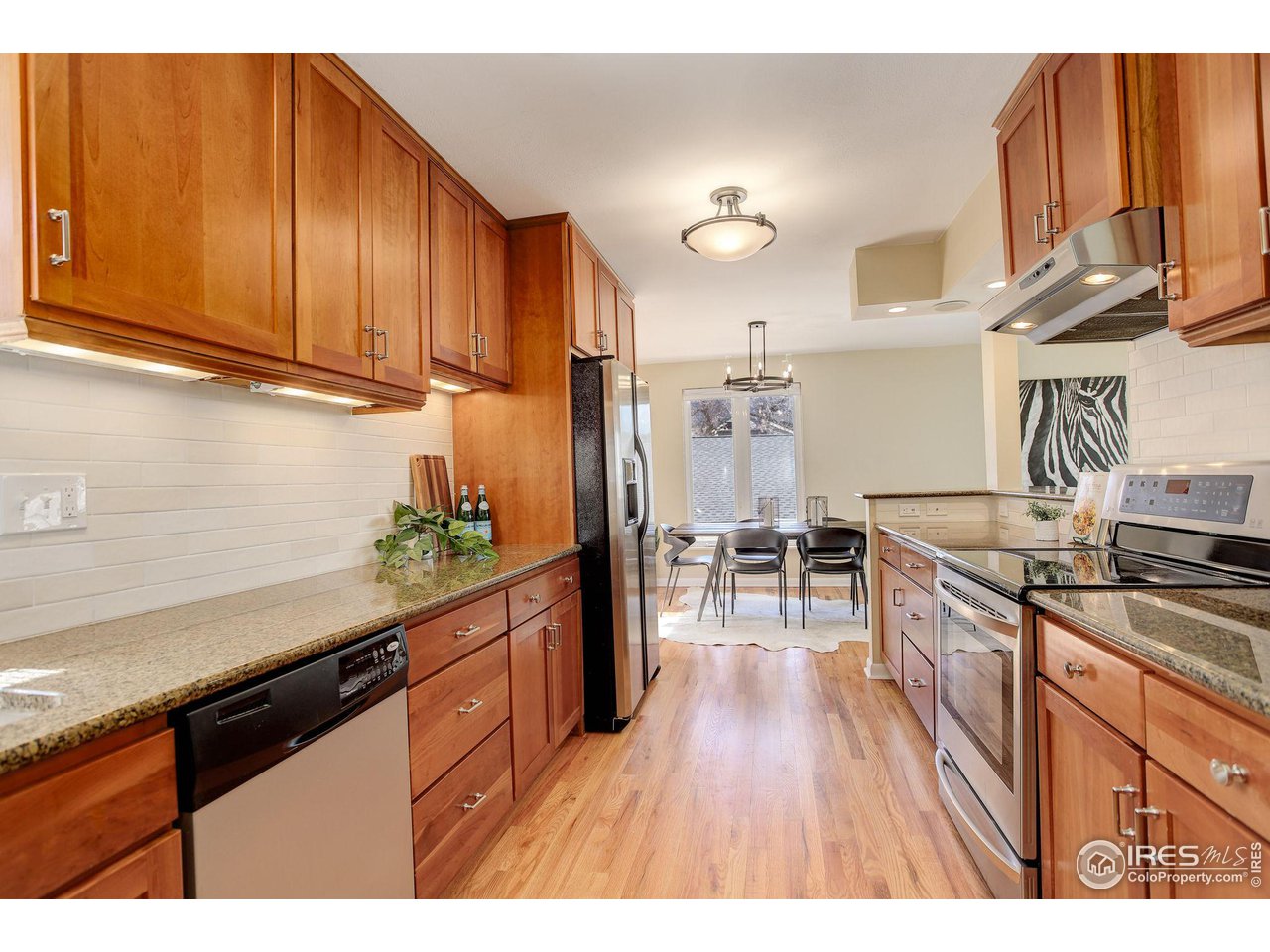 4361 Butler Circle Boulder, CO 80305 - Photo 10 of 39 a kitchen with granite countertop wooden cabinets stainless steel appliances and a wooden floor