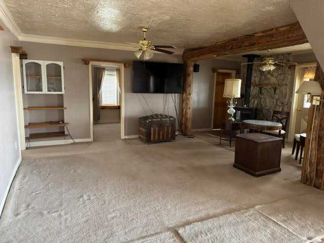 1124 Washam Road Green River, WY 82938 - Photo 21 of 35 Carpeted living area featuring a stone accent wall, wood-finish beams, and ceiling fans