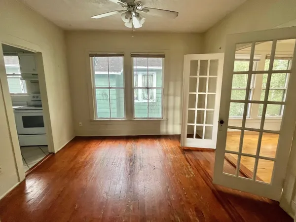 a view of an empty room with a window and wooden floor