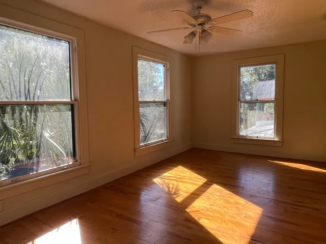 a view of empty room with wooden floor and fan