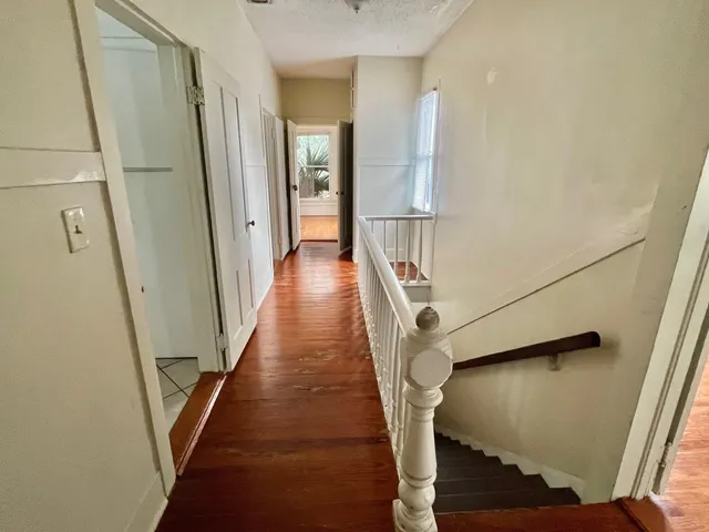 a view of a hallway with wooden floor and staircase