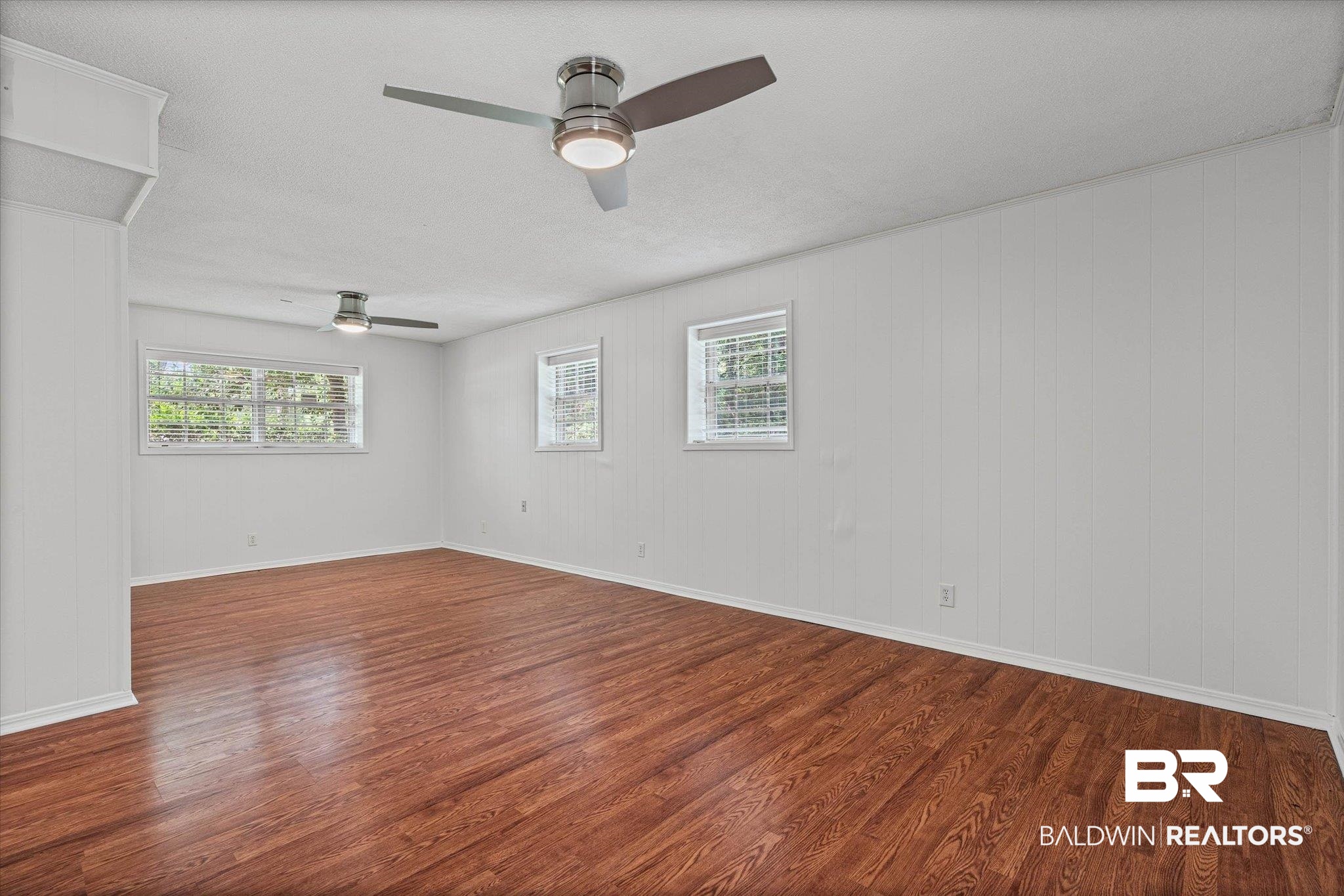8301 Fordham Road Mobile, AL 36619 - Photo 22 of 57 Spacious room featuring wood-finish flooring, white paneled walls, and multiple windows