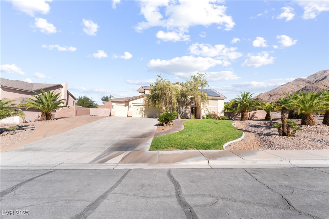 Obstructed view of property featuring solar panels, driveway, a mountain view, stucco siding, and a garage