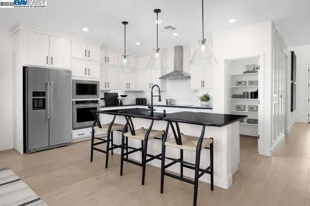 a kitchen with stainless steel appliances kitchen island granite countertop a table chairs refrigerator and microwave