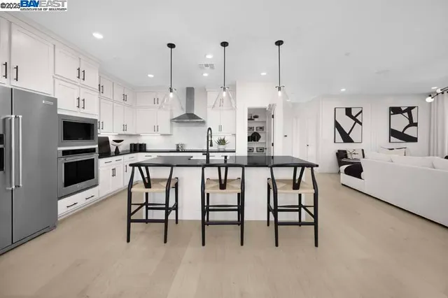 a kitchen with stainless steel appliances kitchen island granite countertop a table chairs sink and cabinets