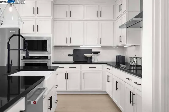 a kitchen with stainless steel appliances granite countertop a sink and dishwasher a stove top oven with white cabinets