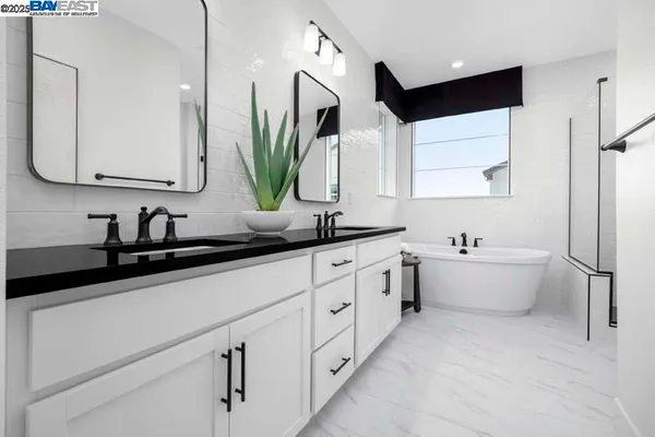 a bathroom with a double vanity sink a mirror and a bathtub