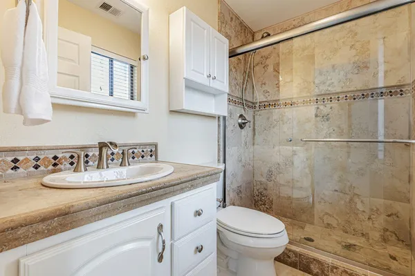 a bathroom with a granite countertop sink a toilet and shower