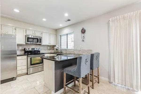 a kitchen with stainless steel appliances granite countertop a stove top oven a sink dishwasher a dining table and chairs with wooden floor