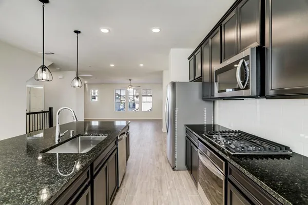 a kitchen with granite countertop stainless steel appliances a sink a stove and a center island