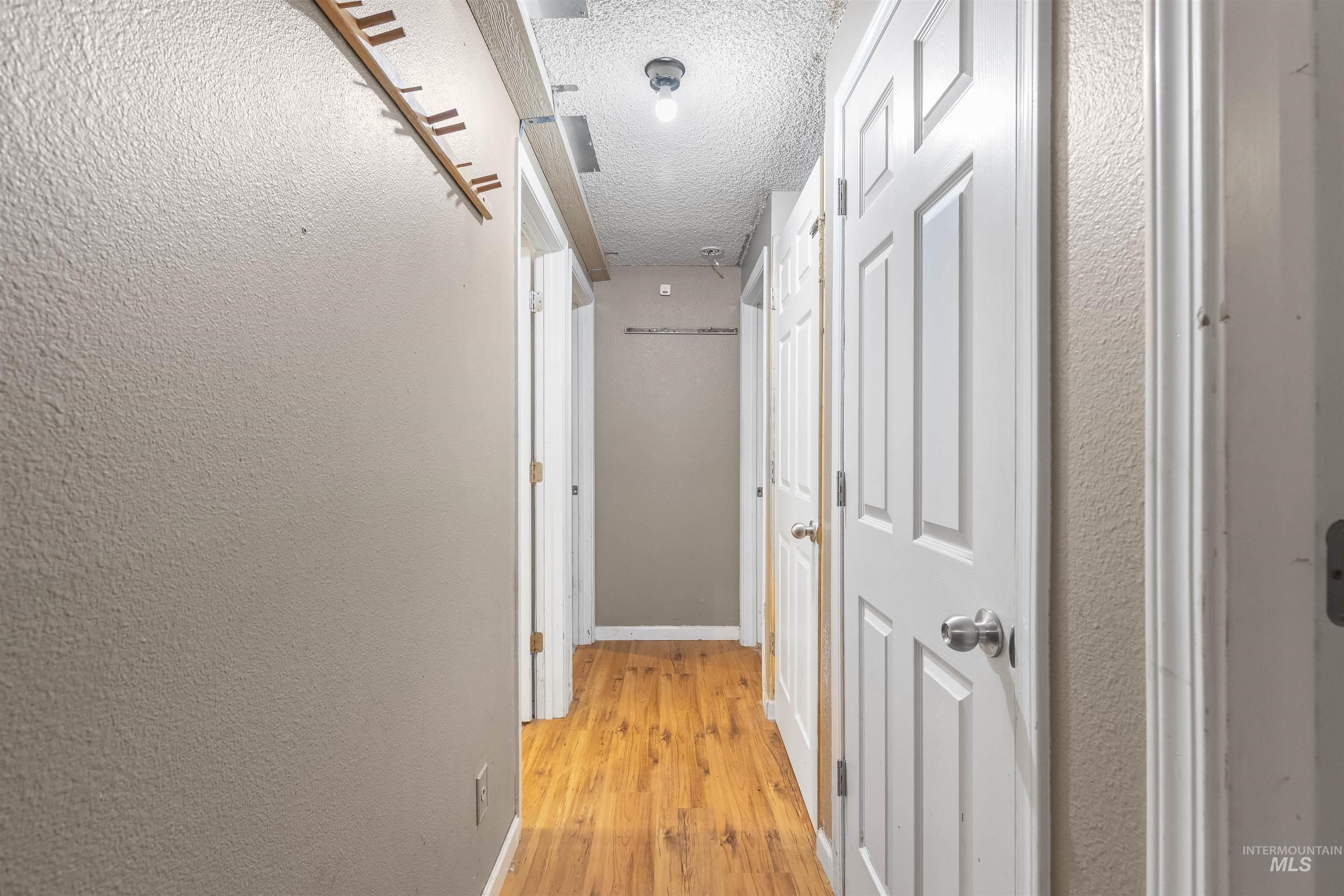 2460 State Street Pomeroy, WA 99347 - Photo 6 of 18 Corridor featuring wood-finish flooring, white paneled doors with spherical hardware, and a textured ceiling