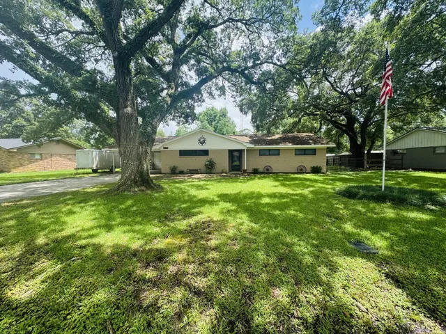 a view of a house with a big yard and large trees