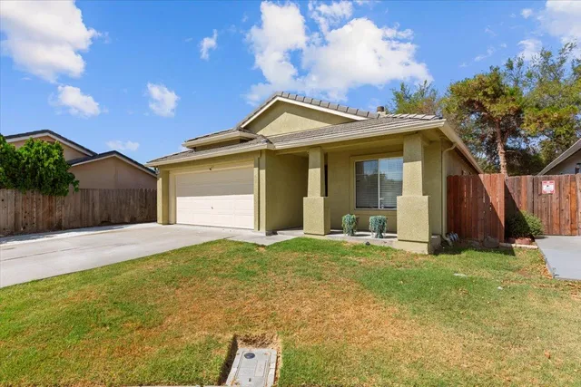 a view of a house with a yard and large tree