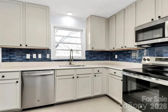 a kitchen with granite countertop white cabinets and a stove