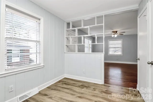 a view of an empty room with wooden floor and a window