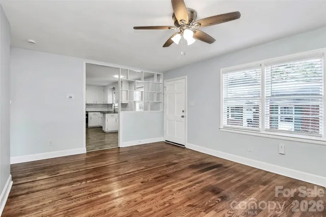 a view of an empty room with a window and wooden floor