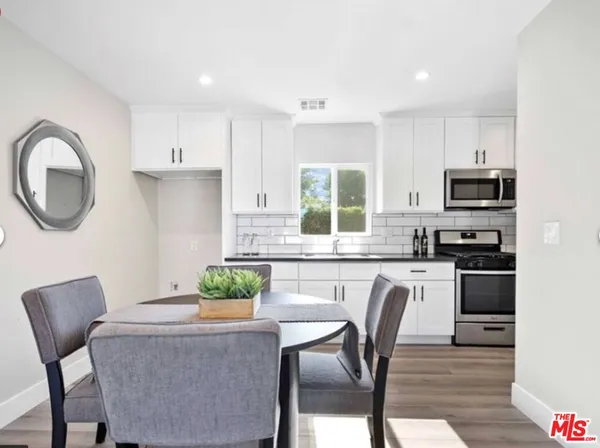 a kitchen with stainless steel appliances granite countertop a stove a microwave a sink a stove a dining table and chairs