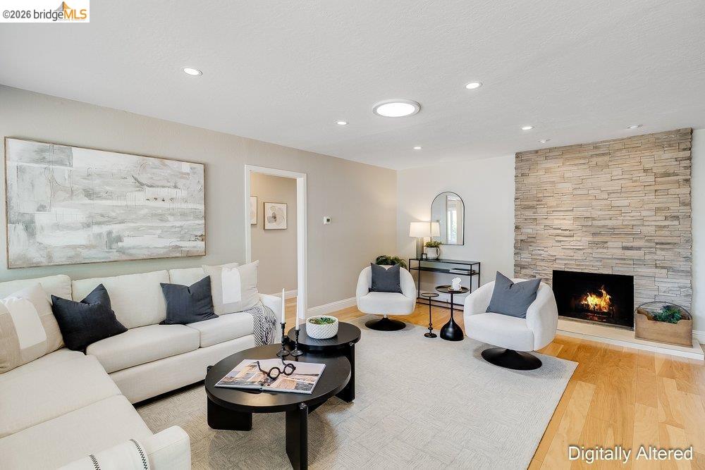 346 Valley View Road Pleasant Hill, CA 94523 - Photo 9 of 57 Living area featuring a floor-to-ceiling stacked stone fireplace, recessed lighting, a circular skylight, wood-finish flooring, and a neutral color palette