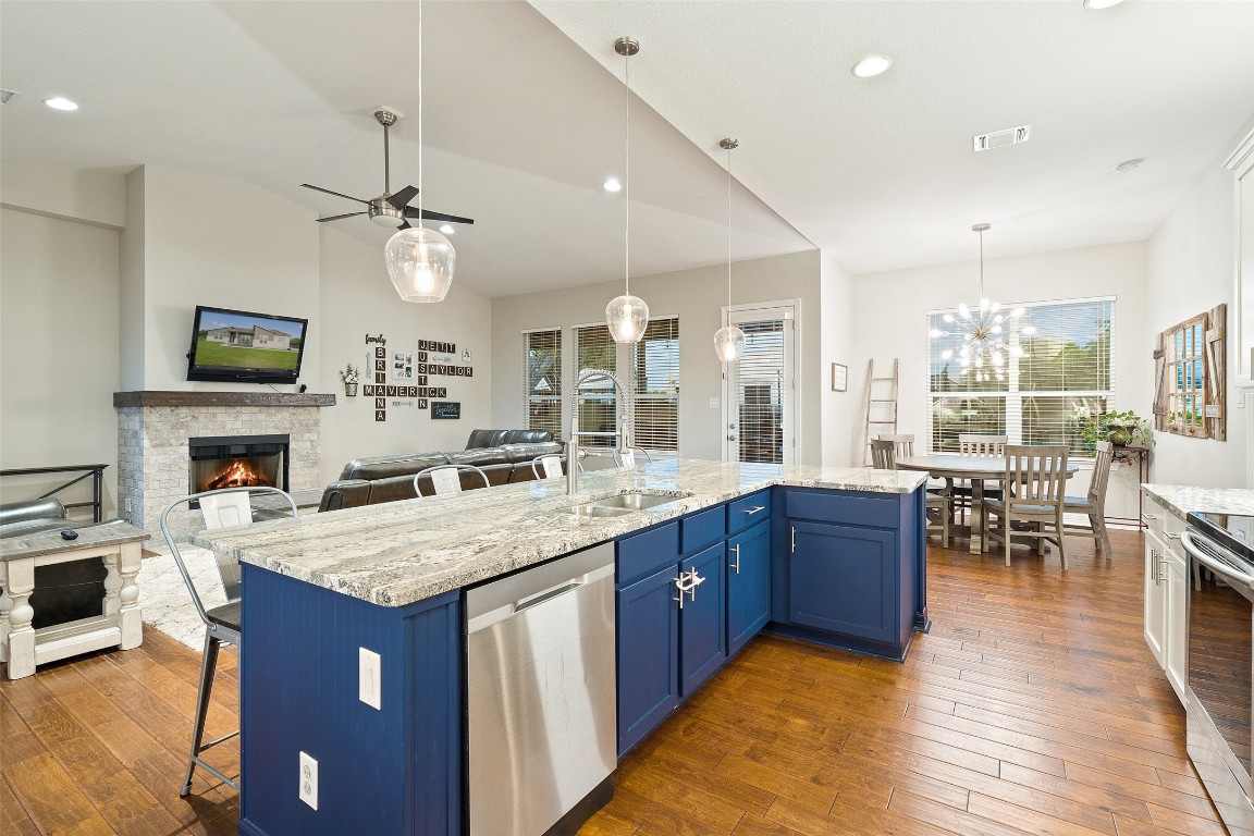 a kitchen with kitchen island granite countertop a stove top oven a sink a dining table and chairs with wooden floor