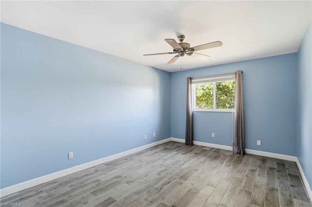 6735 Plantation Manor Loop Fort Myers, FL 33966 - Photo 34 of 46 an empty room with wooden floor chandelier fan and windows