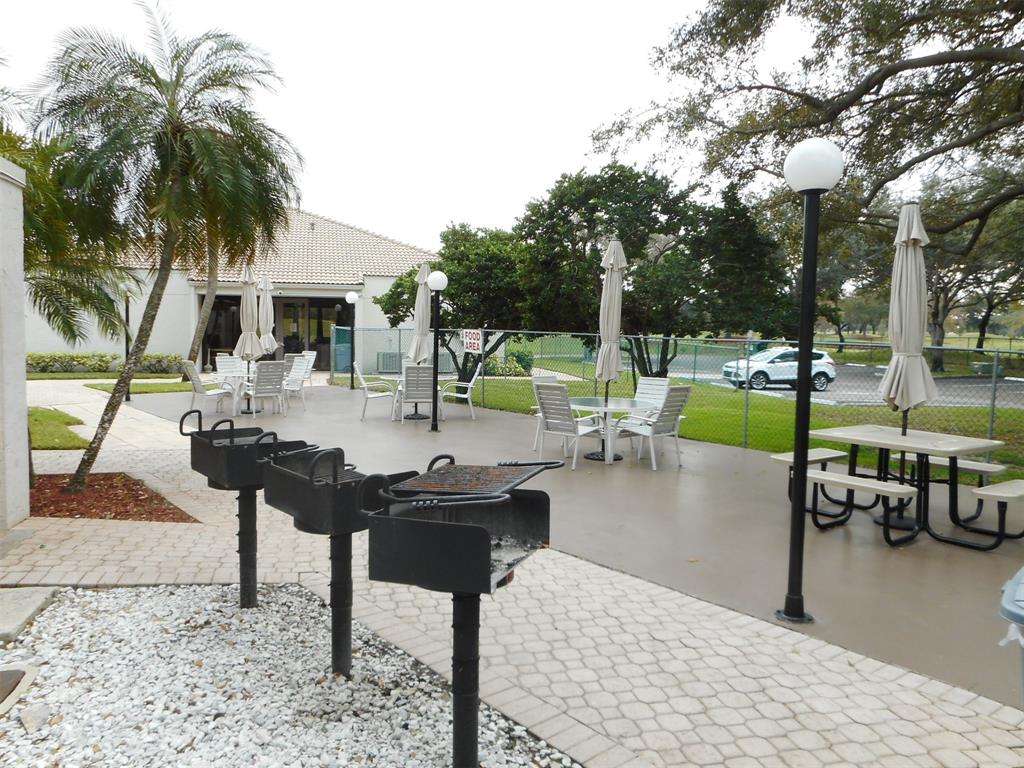 3300 West Rolling Hills Circle, Unit 610 Davie, FL 33328 - Photo 19 of 22 a view of a patio with a table chairs couches and palm trees