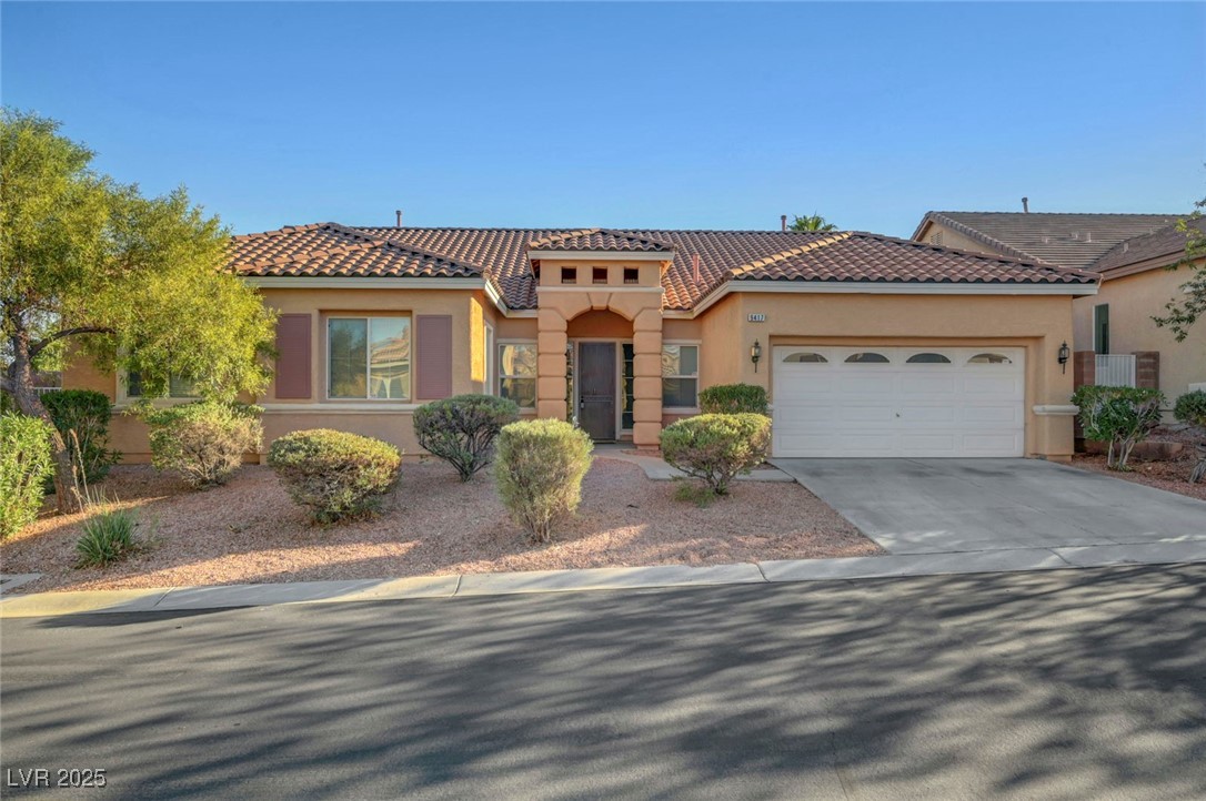 Mediterranean / spanish house featuring stucco siding, driveway, a garage, and a tile roof