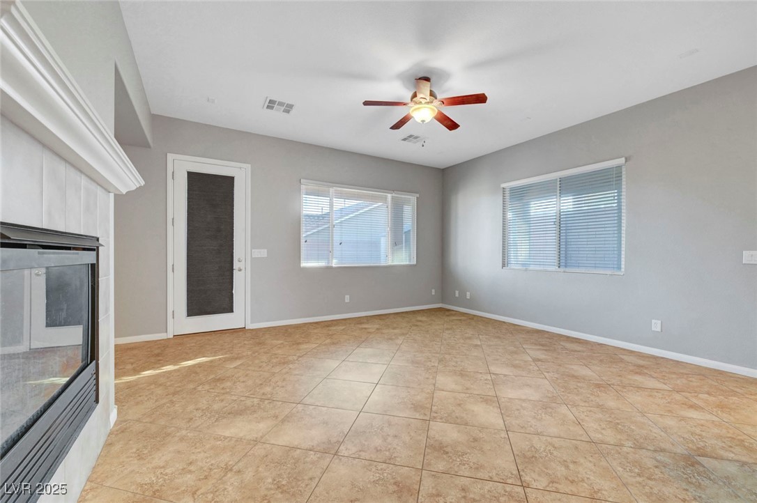 9417 Wisdom Valley Avenue Las Vegas, NV 89149 - Photo 12 of 67 Unfurnished living room with a ceiling fan, light tile patterned floors, and a fireplace
