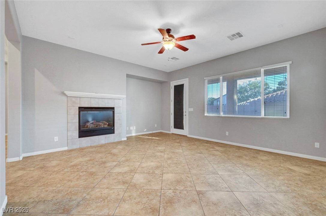 9417 Wisdom Valley Avenue Las Vegas, NV 89149 - Photo 13 of 67 Unfurnished living room featuring a tiled fireplace, a ceiling fan, and light tile patterned floors