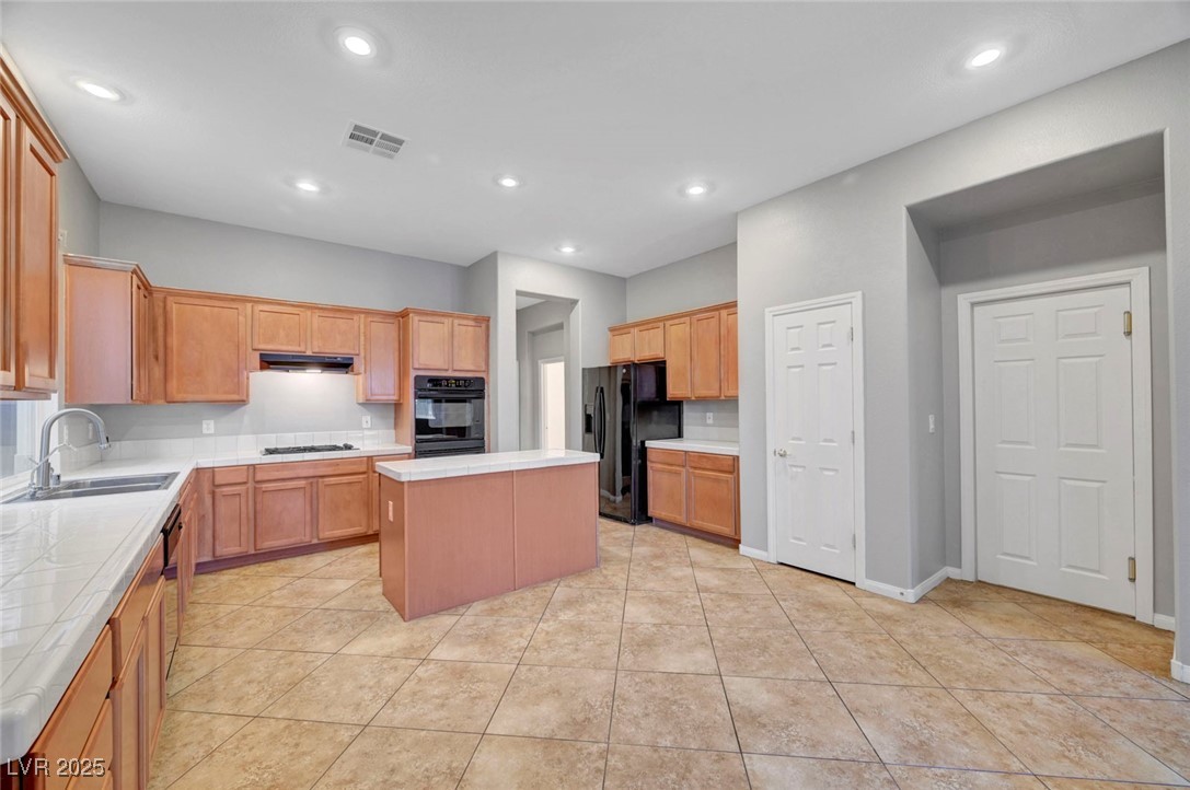9417 Wisdom Valley Avenue Las Vegas, NV 89149 - Photo 17 of 67 Kitchen with a kitchen island, light countertops, black fridge, light tile patterned flooring, and recessed lighting