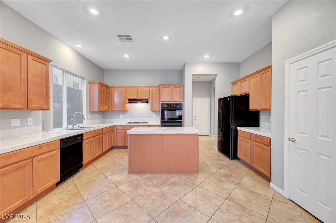 9417 Wisdom Valley Avenue Las Vegas, NV 89149 - Photo 18 of 67 Kitchen featuring a kitchen island, black appliances, light tile patterned floors, recessed lighting, and tile counters