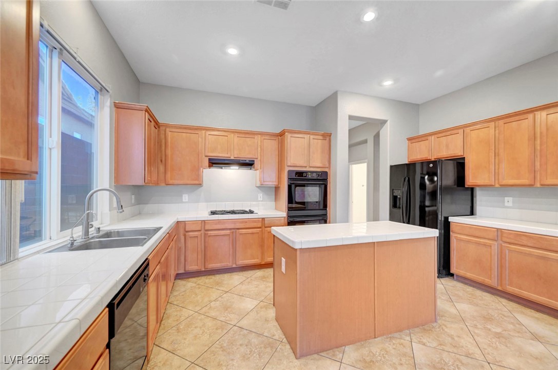 9417 Wisdom Valley Avenue Las Vegas, NV 89149 - Photo 19 of 67 Kitchen featuring tile counters, a center island, black appliances, light tile patterned floors, and recessed lighting