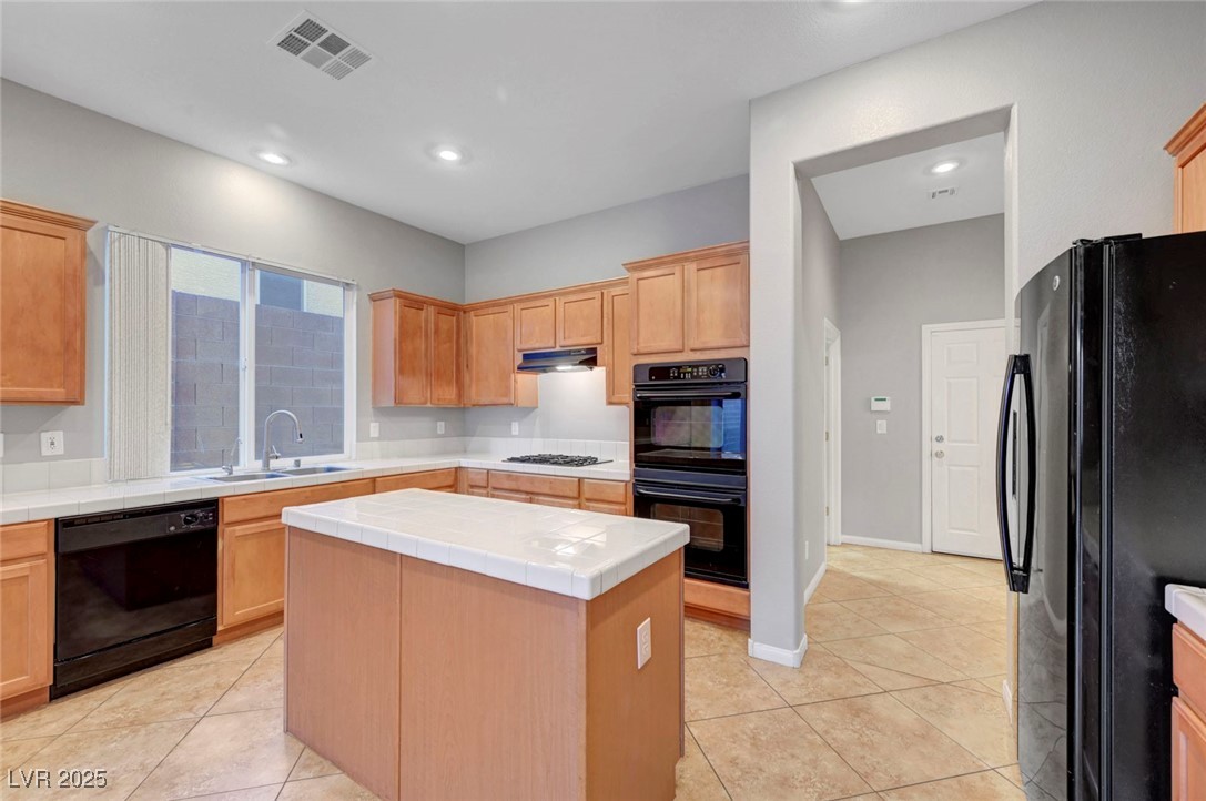 9417 Wisdom Valley Avenue Las Vegas, NV 89149 - Photo 20 of 67 Kitchen featuring tile countertops, black appliances, a center island, light tile patterned floors, and recessed lighting