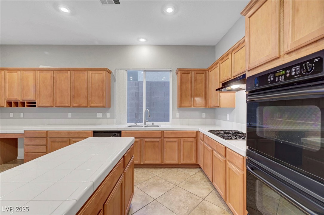 9417 Wisdom Valley Avenue Las Vegas, NV 89149 - Photo 22 of 67 Kitchen with black appliances, light tile patterned floors, tile countertops, under cabinet range hood, and recessed lighting