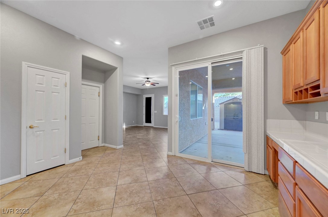9417 Wisdom Valley Avenue Las Vegas, NV 89149 - Photo 24 of 67 Kitchen featuring tile countertops, a ceiling fan, light tile patterned floors, recessed lighting, and brown cabinets