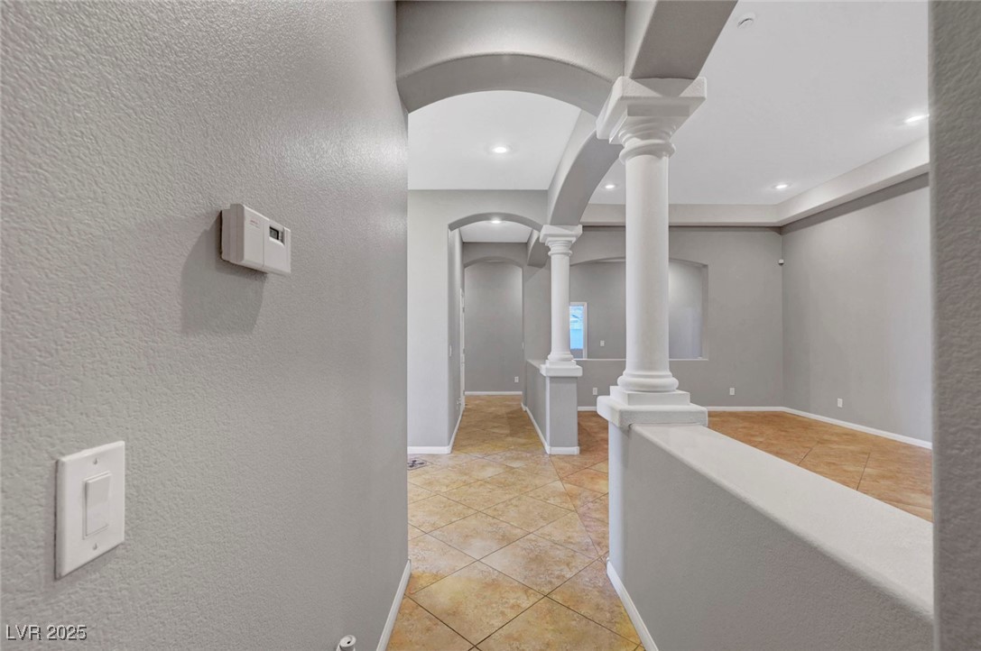 9417 Wisdom Valley Avenue Las Vegas, NV 89149 - Photo 27 of 67 Corridor with light tile patterned floors, arched walkways, a textured wall, and decorative columns