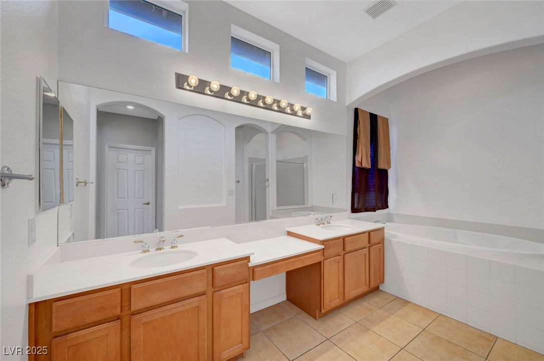 9417 Wisdom Valley Avenue Las Vegas, NV 89149 - Photo 34 of 67 Full bath featuring light tile patterned flooring, a garden tub, double vanity, a shower stall, and a high ceiling