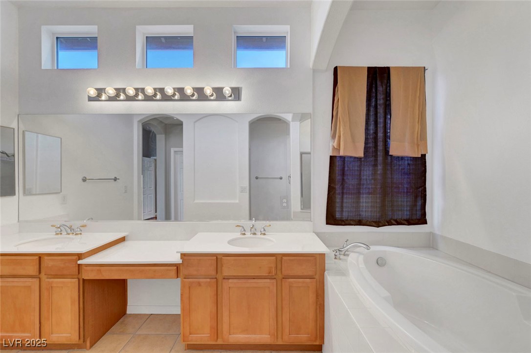 9417 Wisdom Valley Avenue Las Vegas, NV 89149 - Photo 35 of 67 Bathroom with double vanity, light tile patterned floors, a garden tub, and a towering ceiling