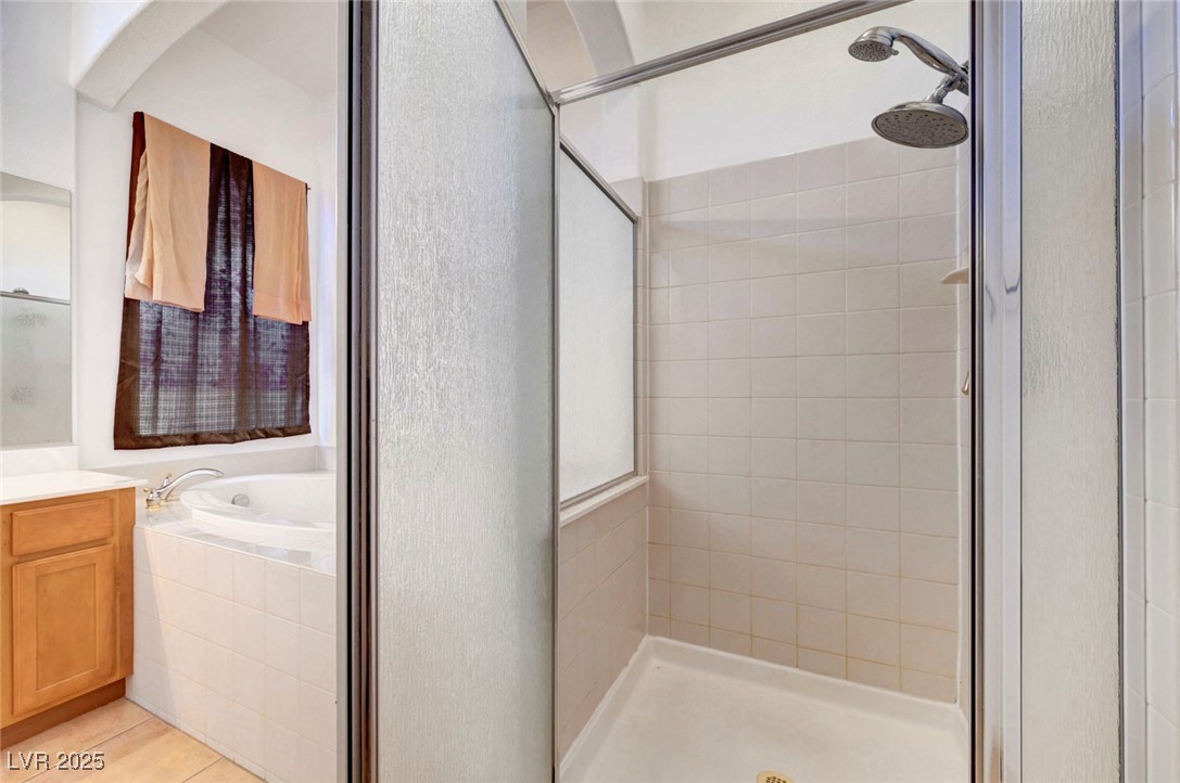 9417 Wisdom Valley Avenue Las Vegas, NV 89149 - Photo 37 of 67 Full bathroom with a stall shower, vanity, a garden tub, and light tile patterned flooring